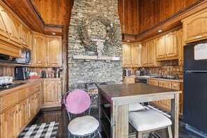 Eine Küche mit Holzausstattung, einer Steinwand, einem Kamin und einem Esstisch mit Stühlen.