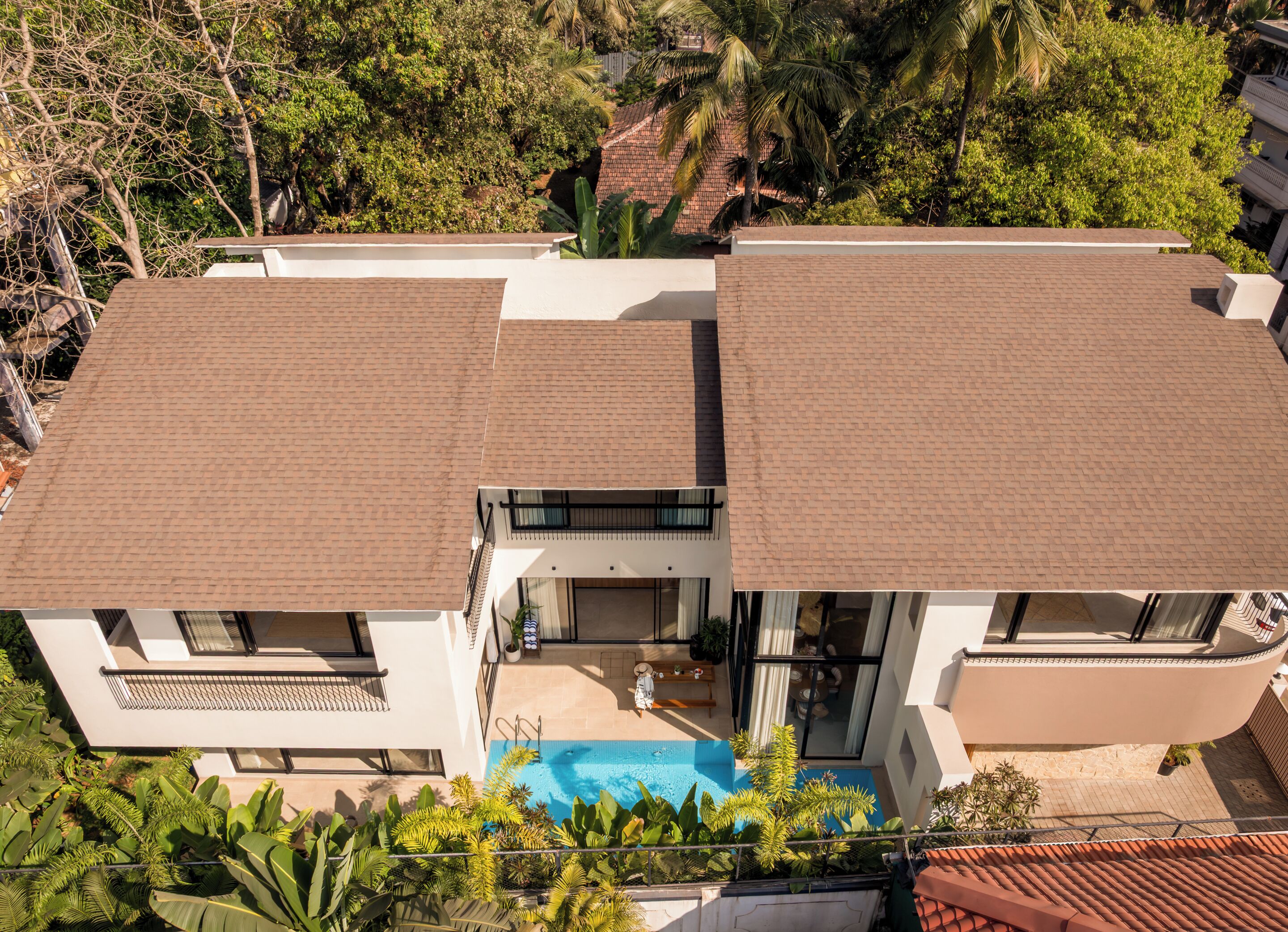Una casa moderna de dos pisos con piscina, ventanas amplias y techo plano.