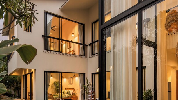 Ein modernes Haus mit Swimmingpool, großen Glasfenstern und einem Balkon.