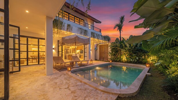 A poolside area with a stone floor, lounge chairs, and a covered seating area. - Sunbeam Oasis (Munggu)