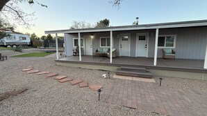 A covered outdoor area with a patio, seating, and a door leading to a building.