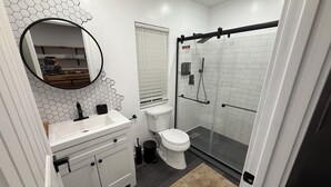 A modern bathroom with a white sink, toilet, and shower.