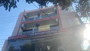 Un bâtiment avec une enseigne indiquant « The Bodyline Gym » et une banderole pour « VANSH PG Unisex ».