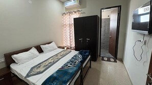 Une chambre à coucher comprenant un lit, une armoire, un téléviseur et un appareil de climatisation.