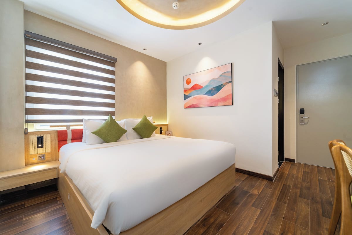 Ein modernes Hotelzimmer mit einem großen Bett, einer Bank, einem Wandbild und einer Tür.