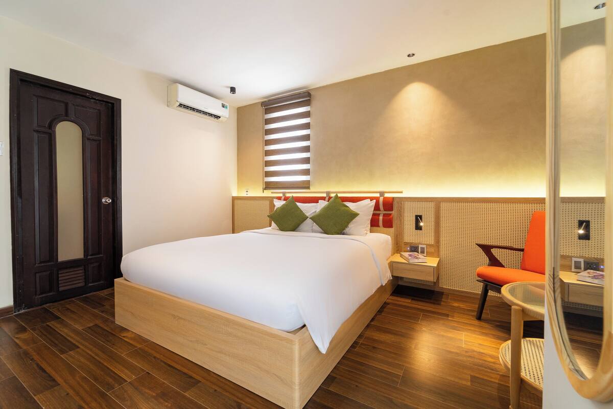 Ein Hotelzimmer mit einem Holzbett, einem Nachttisch, einem Stuhl und einem kleinen Tisch.