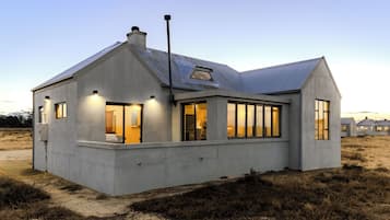 Een modern huis met een betonnen gevel, grote ramen en een schuin dak.