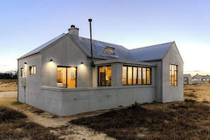 A modern house with a concrete exterior, large windows, and a sloped roof.