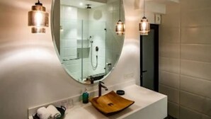 A modern bathroom with a large oval mirror, a wooden basin, and two pendant lights. - TBK VILLA ASSAGAO ZEN (Assagao)