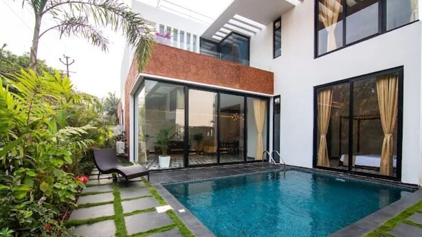 A modern house with a swimming pool, a glass door entrance, and a garden area with a lounge chair. - TBK VILLA ASSAGAO ZEN (Assagao)