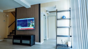 Ein modernes Wohnzimmer mit Flachbildfernseher an der Wand, einer Treppe und einer eingebauten Regaleinrichtung.
