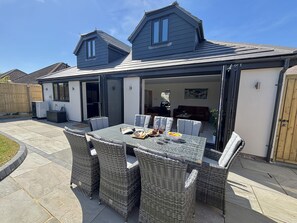 Eine überdachte Terrasse mit Esstisch und Stühlen, einer Couch und einem Bild an der Wand.