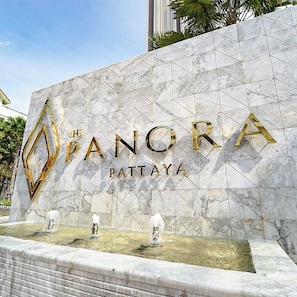 Eine Marmorwand mit dem Text 'The Panora Pattaya' und drei Wasserspielen.