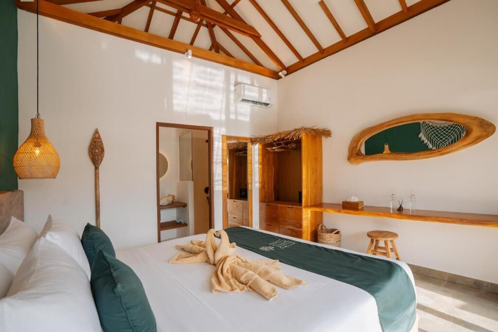 A bedroom with a bed, a wooden ceiling, a mirror, a shelf with toiletries, and a hanging light fixture.