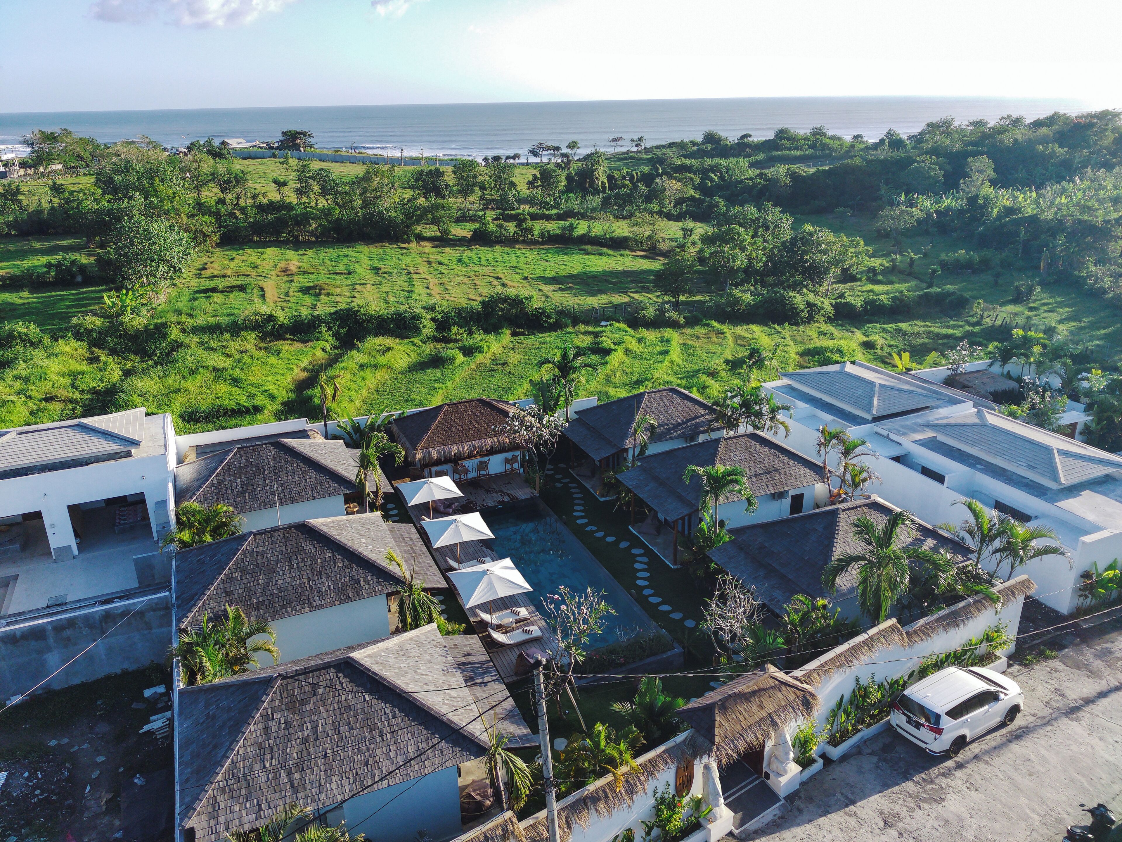 A resort with multiple buildings, a swimming pool, and a view of the ocean.