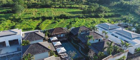 A resort with multiple buildings, a swimming pool, and a view of the ocean.