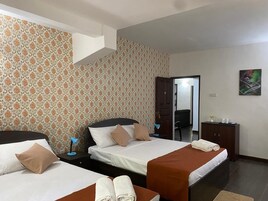 Habitación de hotel con dos camas, un escritorio, una silla, un armario y un cuadro en la pared.