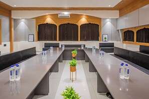 A conference room with long tables, water bottles, and potted plants. - Treebo The Velvet (Gandhinagar)