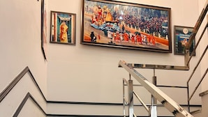 A staircase with granite steps and metal railings, leading to a landing with a large framed painting. - Abhi Ganga Homestay (Haridwar)