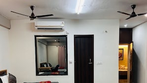 A modern bedroom with a bed, a mirror, a wardrobe, and a ceiling fan. - Abhi Ganga Homestay (Haridwar)