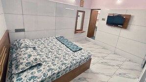 Un dormitorio con cama, ventilador de techo, televisor montado en la pared y un espejo.