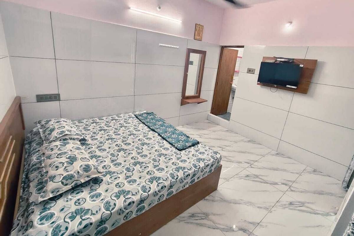 Un dormitori amb un llit, un ventilador de sostre, un televisor fixat a la paret i un mirall.