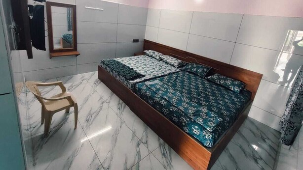 Un dormitorio con una cama, una silla, un ventilador de techo y un espejo.
