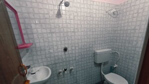 Un baño pequeño con lavamanos, inodoro y ducha blancos.