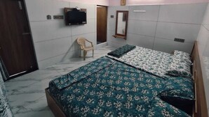 Un dormitorio con dos camas, televisor, una silla y un espejo.