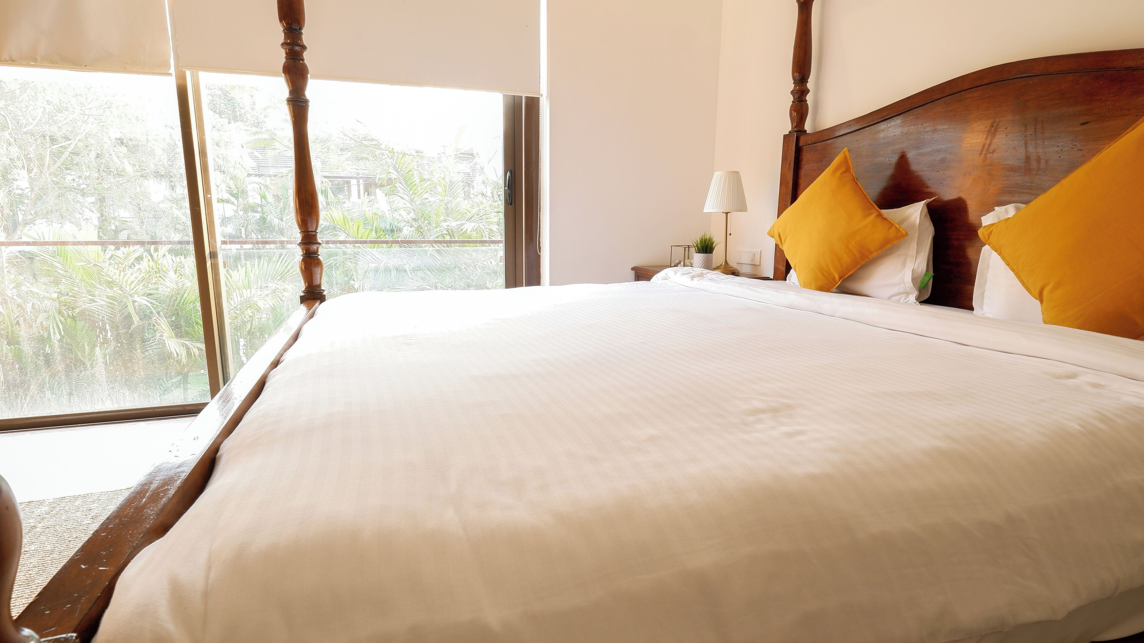 A large bed with a wooden headboard, white bedding, and two yellow pillows.
