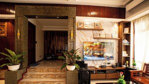 A modern living room with a TV, seating, and decorative plants.
