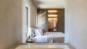 A modern bedroom with a large bed, a bedside table, and a walk-in closet with a hanging rack.