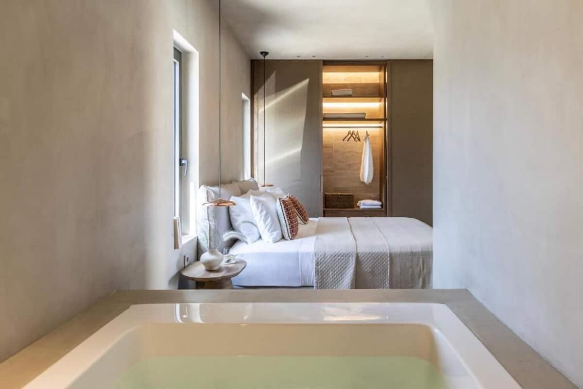 A modern bedroom with a large bed, a bedside table, and a walk-in closet with a hanging rack.
