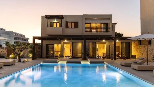 A modern two-story house with a swimming pool in the foreground.