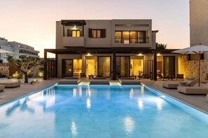 Una casa moderna de dos plantas con una piscina al frente.