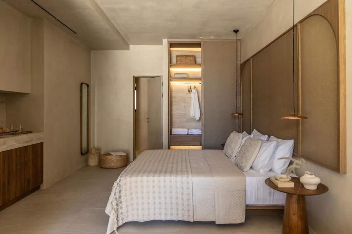 A modern bedroom with a large bed, bedside tables, a wardrobe, and a bathroom visible through an open door.