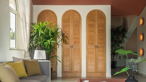 A living room with a grey sofa, a coffee table, a potted plant, and wooden doors in the background. - TBK VILLA VAGATOR   01 (Vagator)