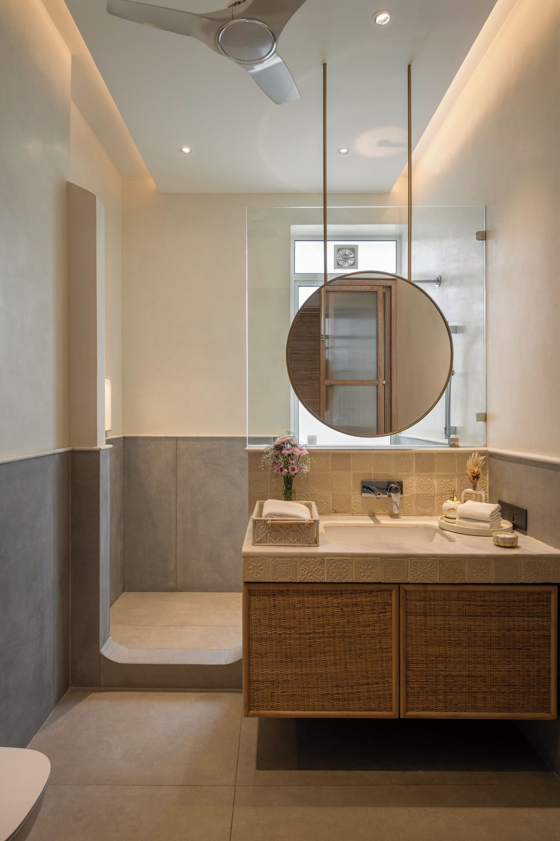 Une salle de bain moderne avec un grand miroir, une baignoire et un meuble-lavabo doté d'un placard en osier.
