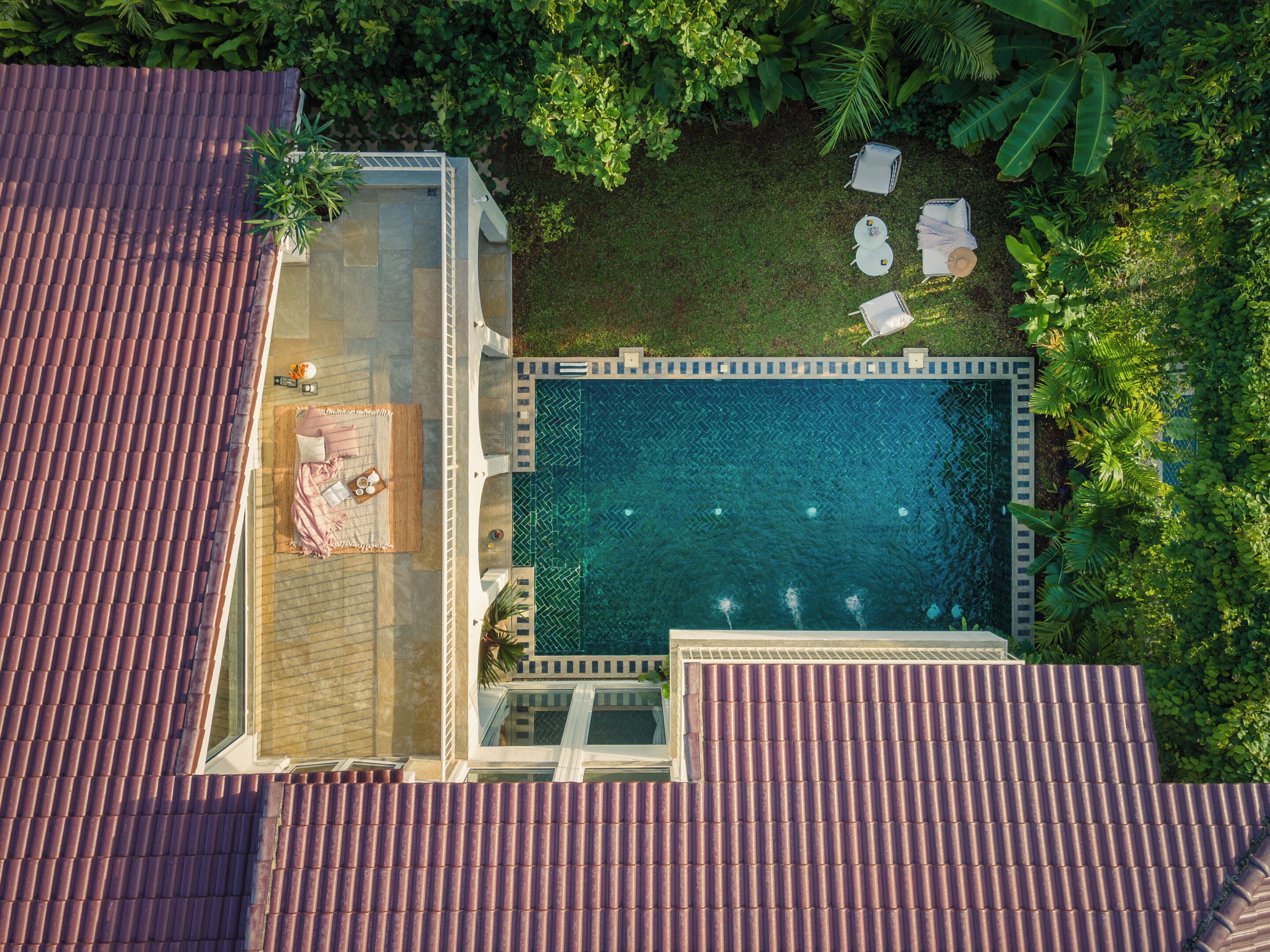 Vue aérienne d’un espace piscine sur le toit, avec une piscine, des chaises longues et un petit coin salon.