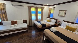 A hotel room with two single beds, a sofa, and a small table.