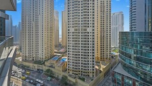 A high-rise building with multiple floors, a central courtyard, and surrounding modern architecture. - Bloomfields Signature 1BR Bay Central We (Dubai)