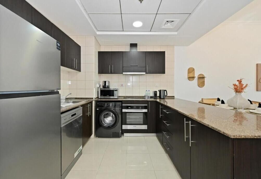 A modern kitchen with dark cabinetry, a built-in washing machine, and a microwave.