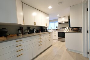 A modern kitchen with white cabinets, stainless steel appliances, and a light wood floor. - Modern North Beacon Hill Retreat - Sauna & Hot Tub (Seattle)