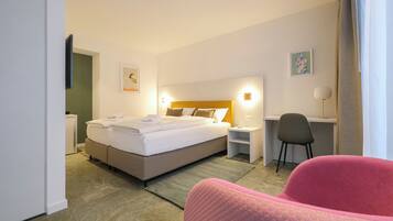 A hotel room with a bed, bedside tables, a desk, a chair, and a painting on the wall.