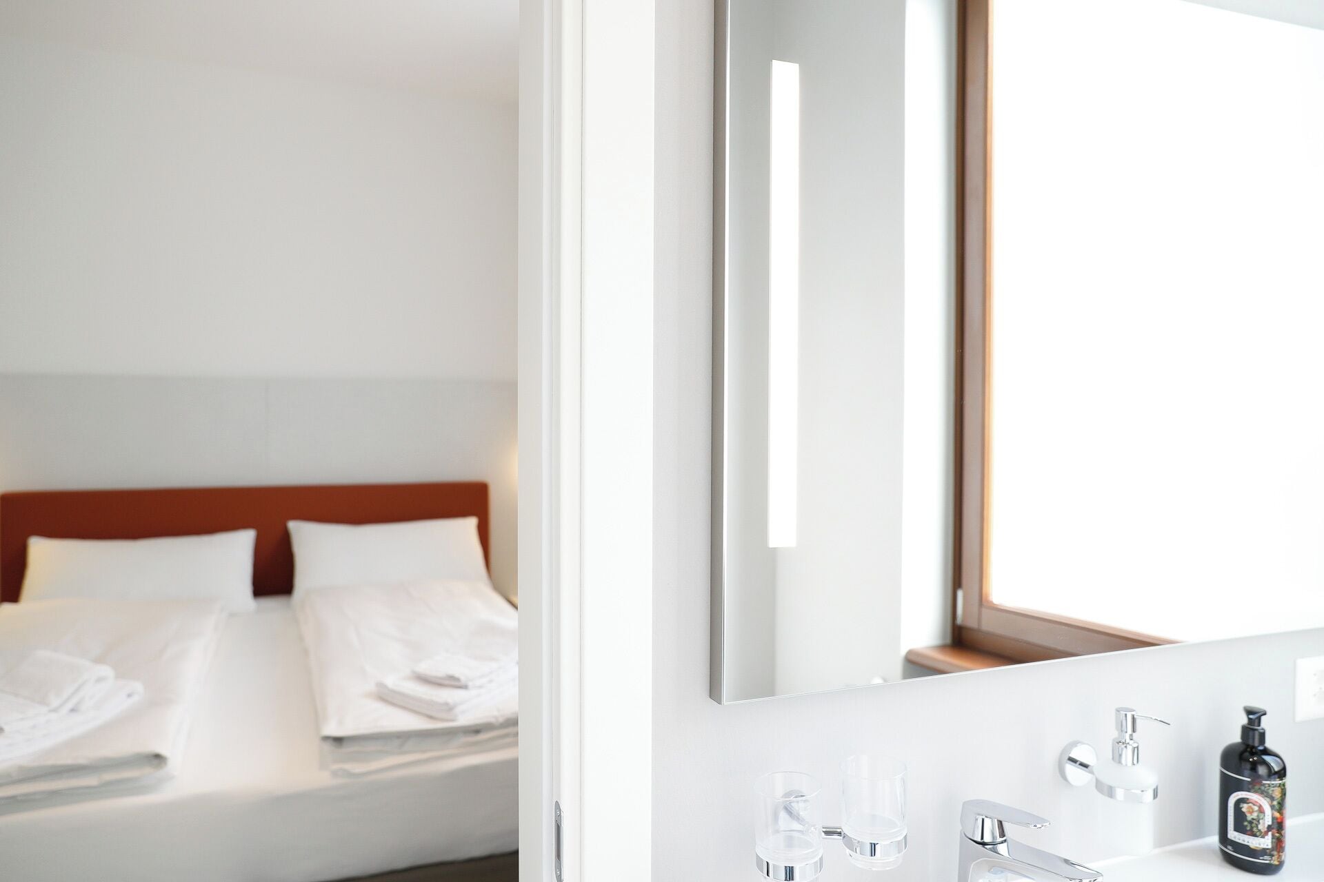Une chambre d’hôtel avec un lit, une salle de bain avec un miroir et une fenêtre.