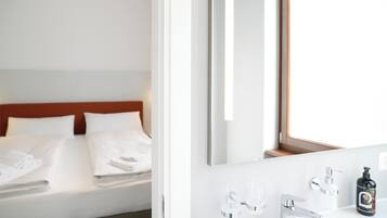 Une chambre d’hôtel avec un lit, une salle de bain avec un miroir et une fenêtre.