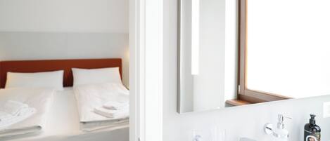 Una habitación de hotel con cama, baño con espejo y ventana.