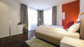 Une chambre d’hôtel moderne, dotée d’un grand lit, d’un bureau et d’une chaise.