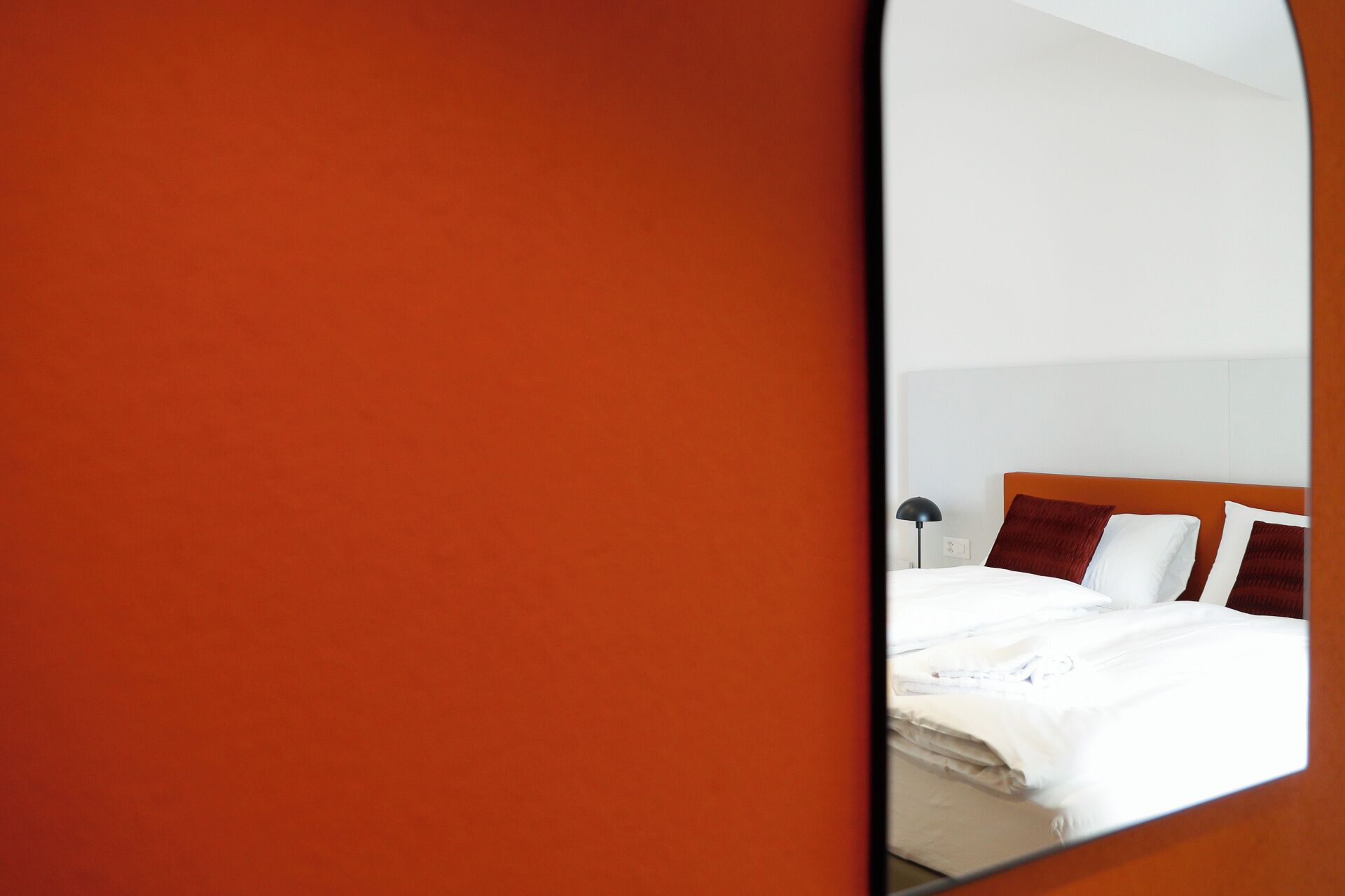 A hotel room with a bed, a nightstand, and a lamp.