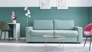 A teal-colored sofa, a round glass coffee table, a pink chair, a white side table, and a floor lamp with white globes. - Boutique Hotel Piazza Grande Locarno  (Locarno)